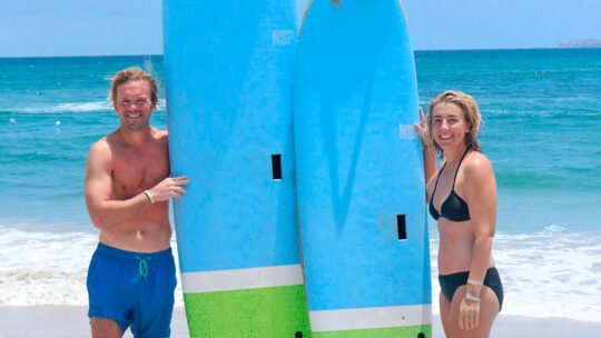 Couple smiling with surfboards after their lesson at La Lancha beach