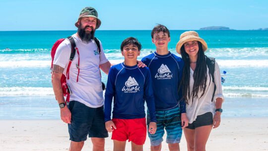 Family posing happily at La Lancha beach after their surf lesson