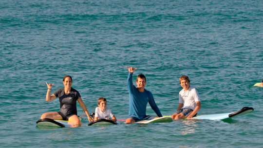 Family on surfboards waving in Punta Mita