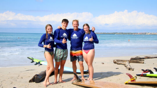 Smiling family with surfboards on the sand in San Pancho