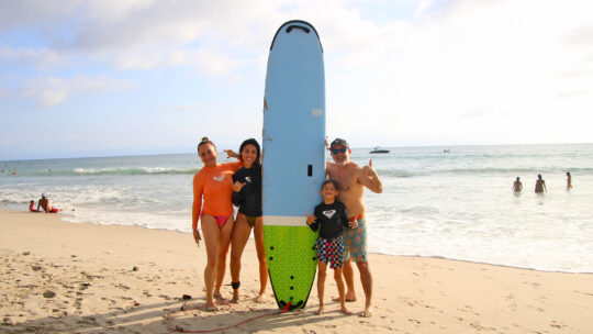 Family with surfboard by the ocean