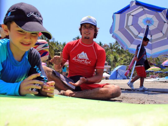 bilingual instructor fitting rash guard before kids surf lessons in sayulita