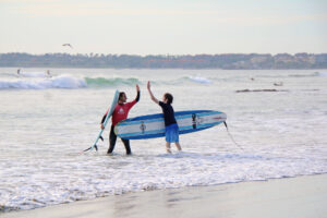 Teen surfer and Wildmex instructor high-fiving after a surf session at La Lancha beach