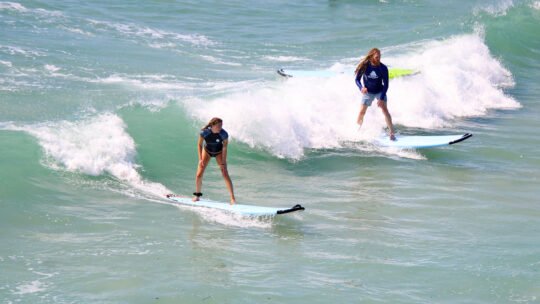 Two surfers sharing a wave during Wildmex Surf Camp session