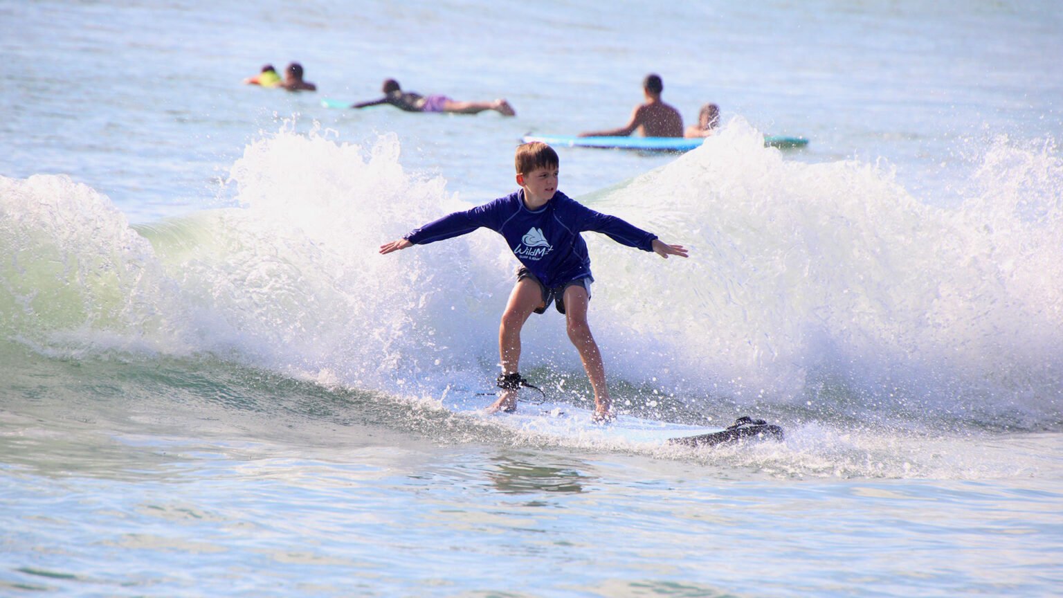 Young boy surfing a wave during WildMex kids surf lesson in Punta Mita