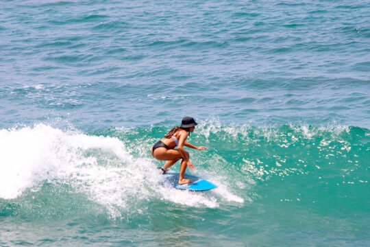 Surfer riding a wave at La Lancha beach after shuttle pickup from San Pancho
