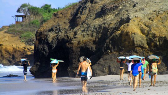 Surfers walking with boards toward the surf break during WildMex Surf Camp in Mexico