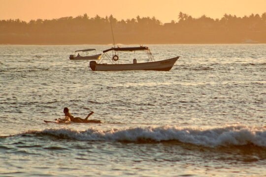 Surfer paddling out at sunset at La Lancha beach, reachable from San Pancho