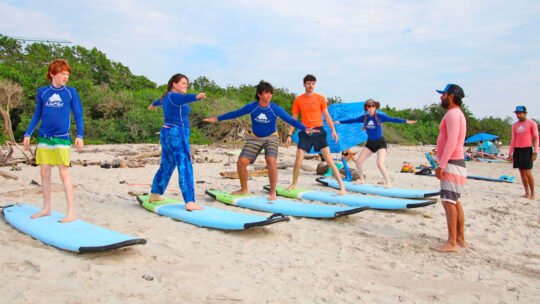 Group of surfers receiving instructions from a WildMex instructor during a land session before entering the water
