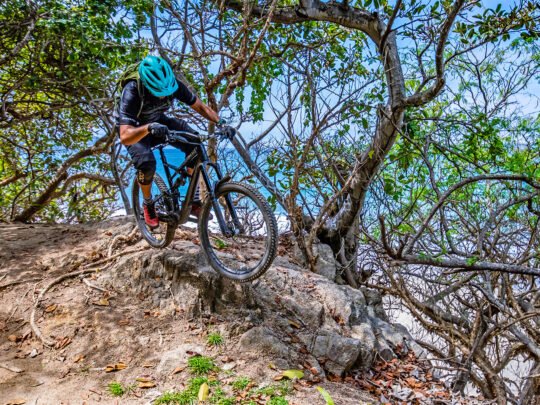 Mountain biker riding jungle trail with ocean view in Sayulita, Mexico