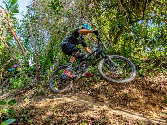 Two mountain bikers riding fast on jungle trail in Sayulita