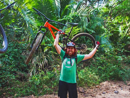 Mountain biker carrying bike during WildMex tour in Sayulita