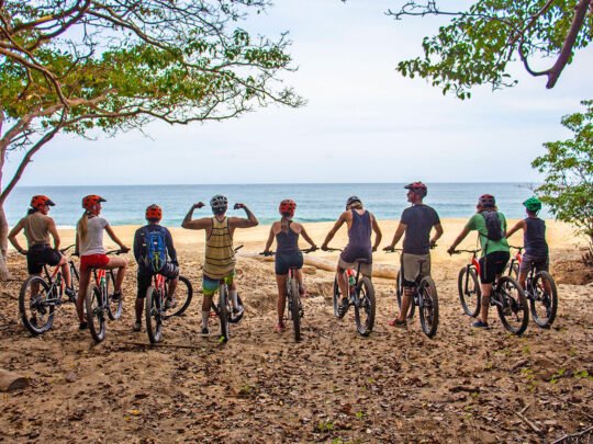 Group of mountain bikers posing with ocean view after trail ride