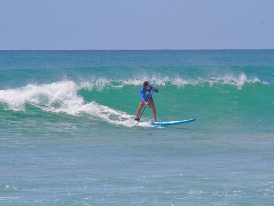 Man riding a wave on paddle board in Punta Mita during advanced SUP lesson