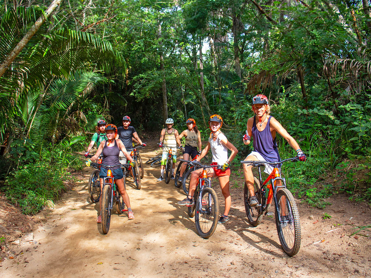 Cyclists smiling on Punta Sayulita trail framed by abundant tropical vegetation