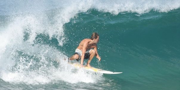 Javier Chavez, CEO of WildMex, riding a surfboard on a wave in Mexico