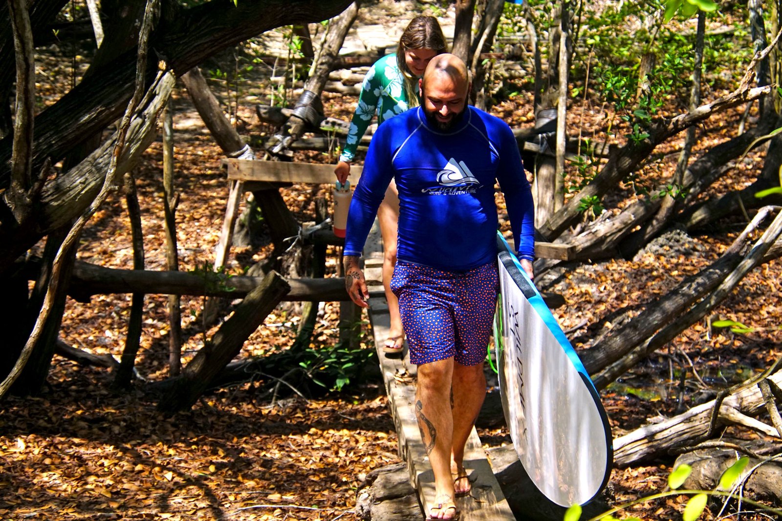 People walking with surfboards through the protected mangrove and jungle trail access to La Lancha.